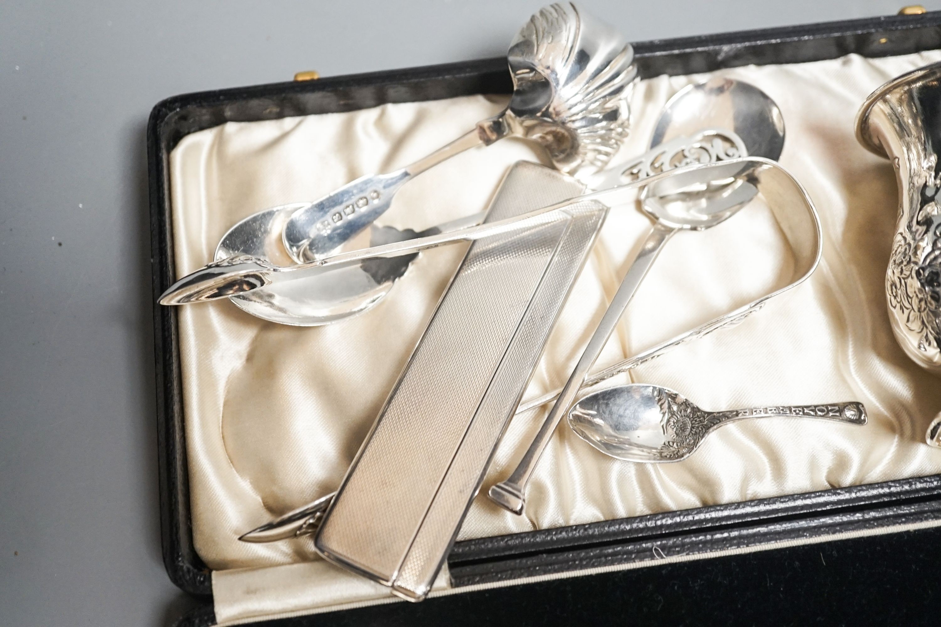 A cased pair of silver serving spoons, a silver christening mug and minor silver flatware, comb, etc.